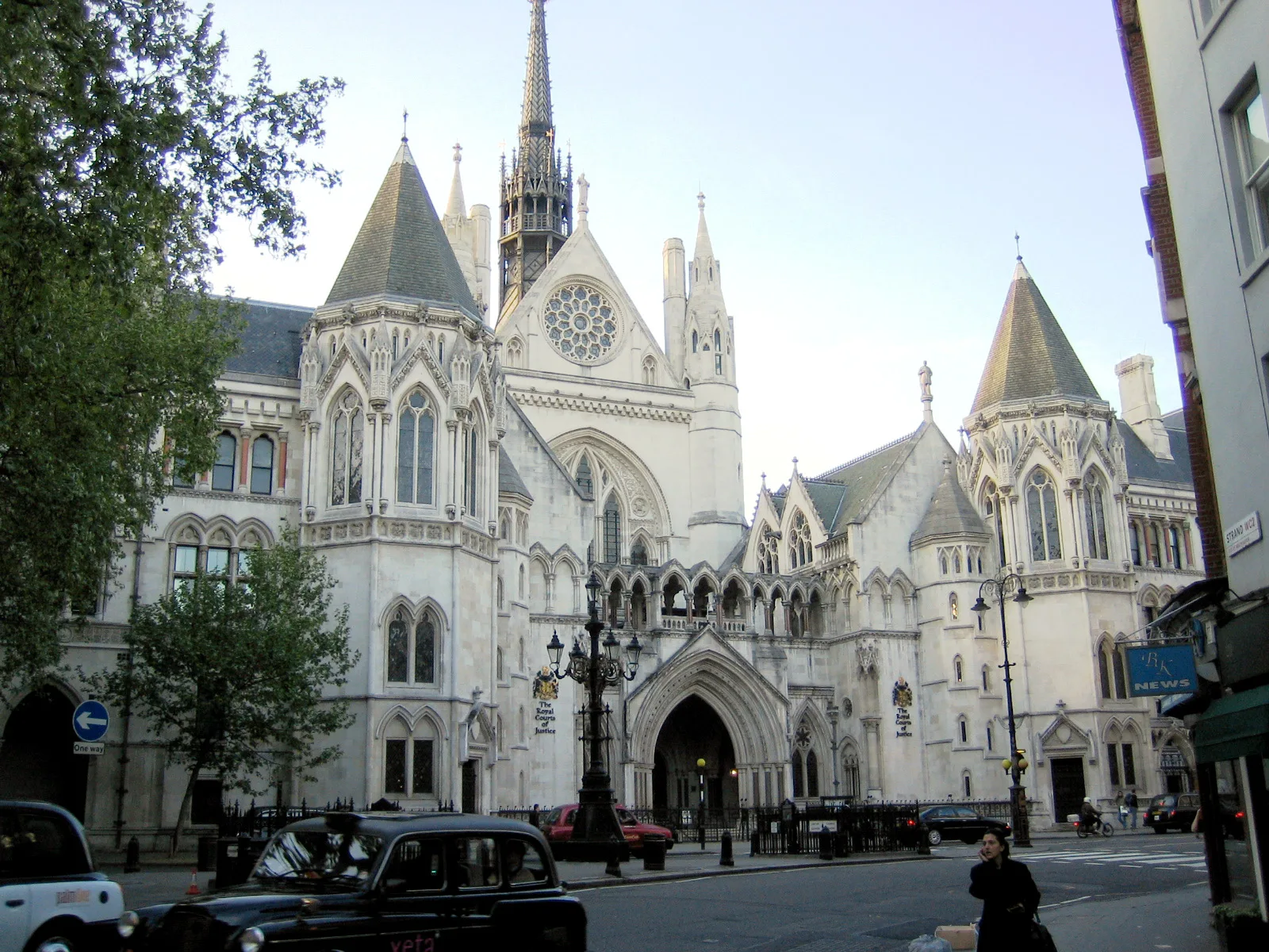 The pale stone Gothic Revival front of the Royal Courts of Justice on the Strand, with pointed arches, turrets and a tall spire.
