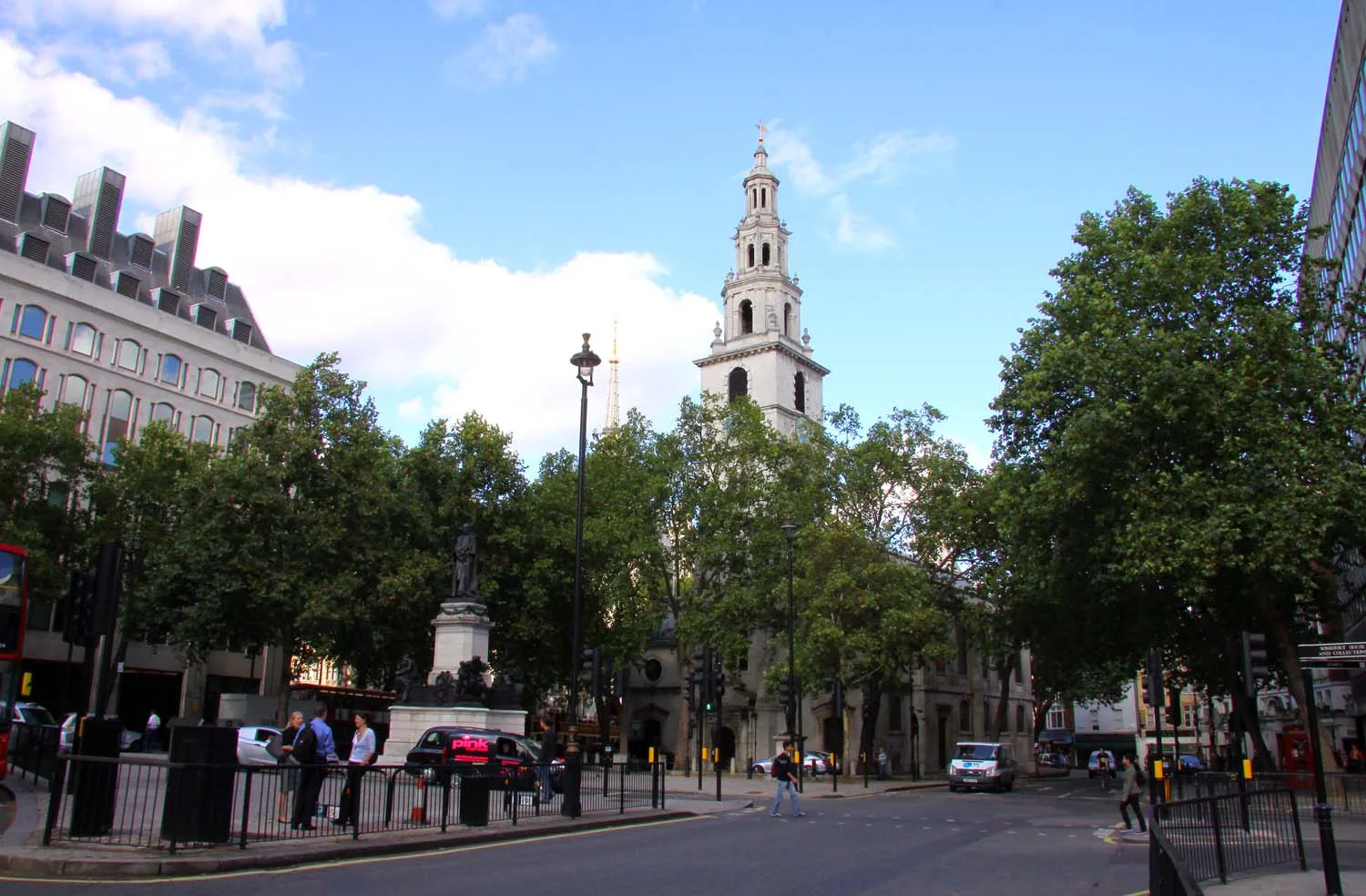 The white stone church of St Clement Danes with its tiered steeple, standing on an island in the traffic of the Strand.